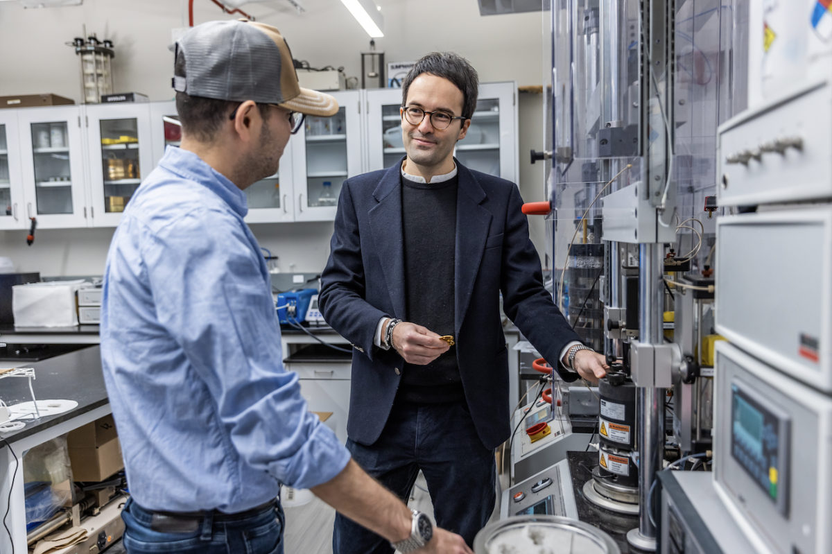 SOIL Director Alessandro Rotta Loria estimates that on average, heat islands underneath urban areas are warming by 2.5 degrees Celsius per decade globally.
Alt text: Two people stand in front of a testing device for electrical experiments in an engineering laboratory.